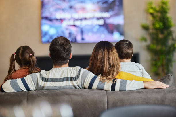 vista posteriore di una famiglia che guarda la tv a casa. - family television watching watching tv foto e immagini stock