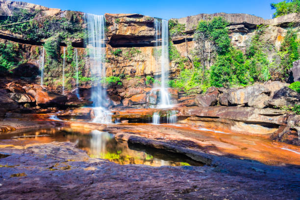 istock waterfall falling from mountain top with reflection and blue sky at day from low angle 1392124050