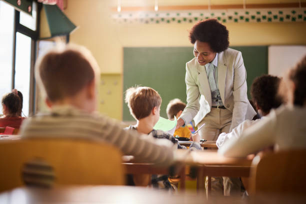 istock Happy African American teacher assisting her students on a class at elementary school. 1392124125