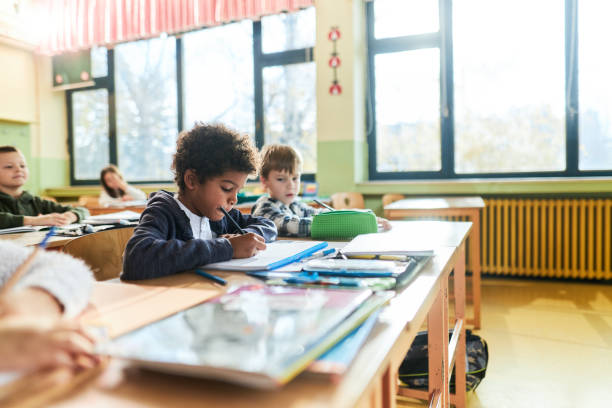 istock Black schoolboy and his friends on a class at elementary school. 1392124222