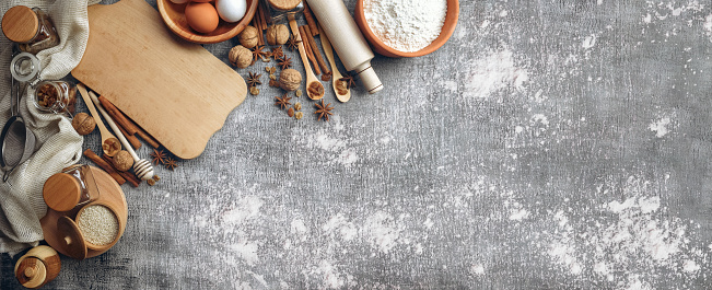 Baking love. Bakery background. Baking ingredients and kitchen utensils on the black background. Flour, almond nuts, eggs. Top view. Modern cooking composition. Spices and food products.
