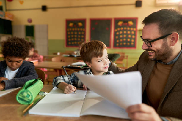 istock Happy professor talking to schoolboy on a class at school. 1392124812