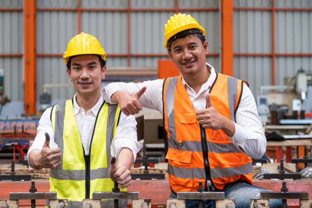 istock Selective focus at Asian men mechanical engineer, wearing safety equipment. While doing machine maintenance and safety control inside of factory area. With blurred background of heavy machine. 1392125196