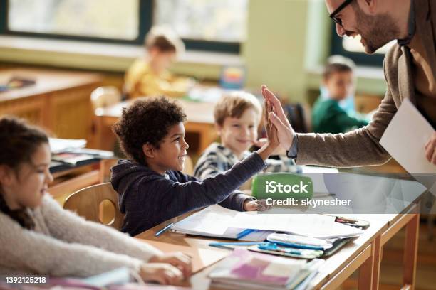 Happy Teacher And Schoolboy Giving Each Other Highfive On A Class Stock Photo - Download Image Now