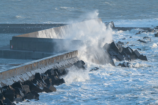Waves from stormy weather in the north sea breaking against the wall at the entrance to Aberdeen Harbour, Scotland.