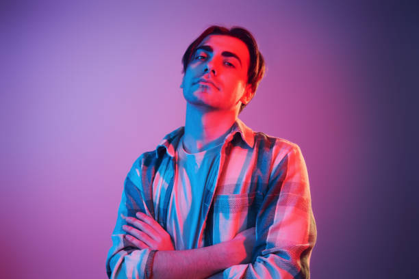 istock Arms crossed. Man standing in the studio with neon light 1392128556