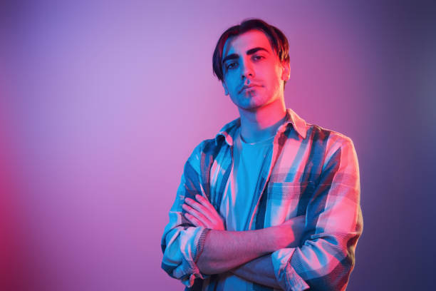 istock Arms crossed. Man standing in the studio with neon light 1392128559