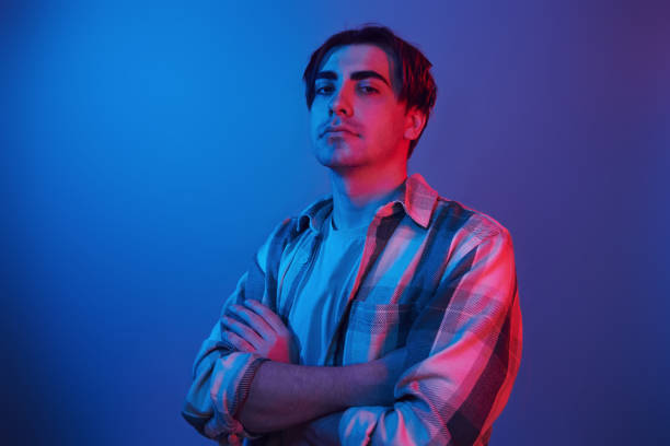 istock Arms crossed. Man standing in the studio with neon light 1392128583