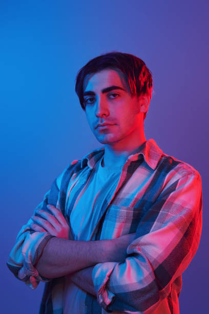istock Arms crossed. Man standing in the studio with neon light 1392128585