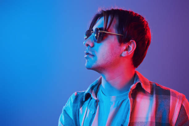istock Stylish look. Man standing in the studio with neon light 1392128589