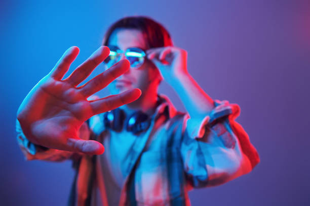 istock Stylish look. Man standing in the studio with neon light 1392128602