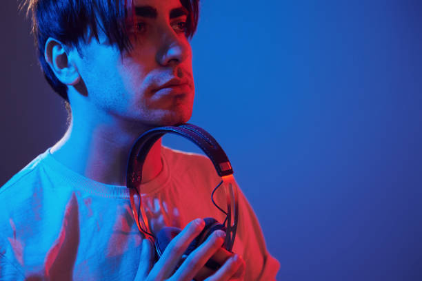 istock Holding headphones in hands. Man standing in the studio with neon light 1392128691