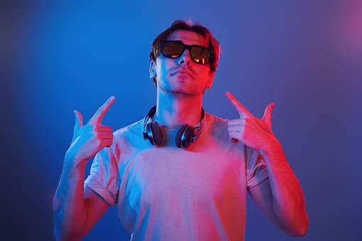 Showing gestures. Man standing in the studio with neon light.