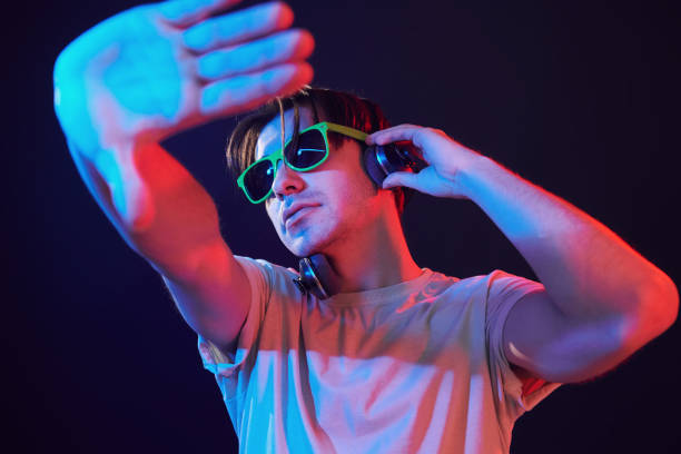istock Dj is having fun. Man standing in the studio with neon light 1392128725