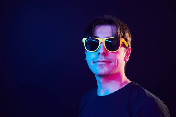 istock In yellow sunglasses. Man standing in the studio with neon light 1392128772