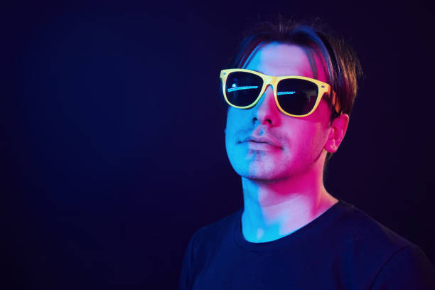 istock In yellow sunglasses. Man standing in the studio with neon light 1392128786
