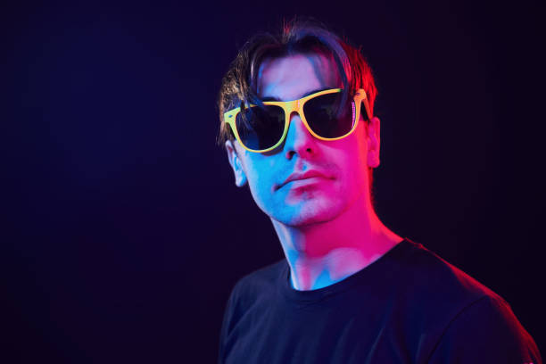 istock In yellow sunglasses. Man standing in the studio with neon light 1392128801