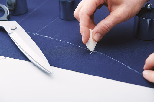 Tailor makes markings with chalk on the fabric. Clothes sewing. Tailoring. Close up view