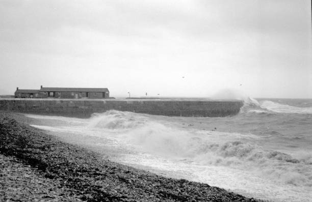 Stormy day on the Jurassic Dorset coast with large waves splashing against the famous Cobb protecting sea wall, 35mm film.
