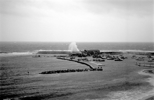 Stormy day on the Jurassic coast with large waves pounding the protecting sea wall, the Cobb, 35mm film.