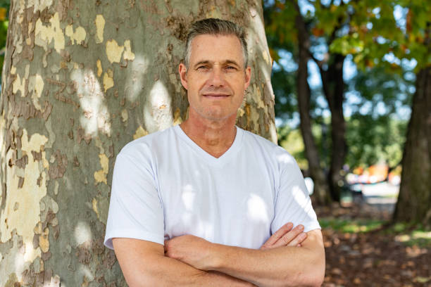 istock A handsome man leaning on a tree with his arms folded and looking at the camera 1392134398