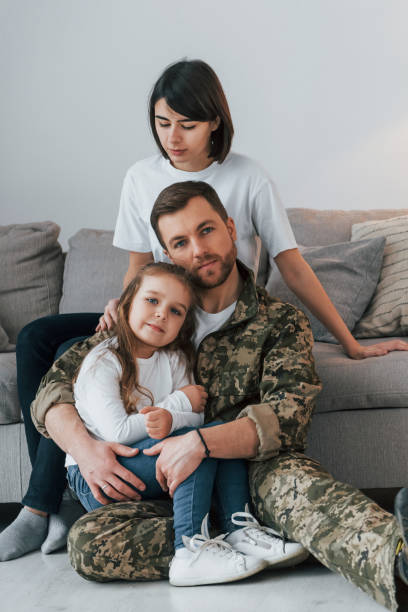 embracing each other. soldier in uniform is at home with his wife and daughter - domestic life young family family child imagens e fotografias de stock