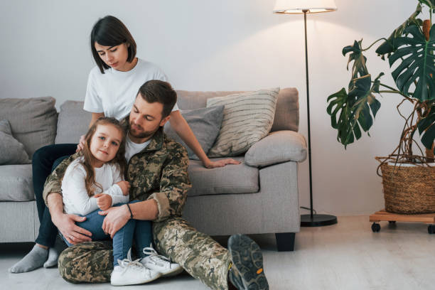 embracing each other. soldier in uniform is at home with his wife and daughter - domestic life young family family child imagens e fotografias de stock