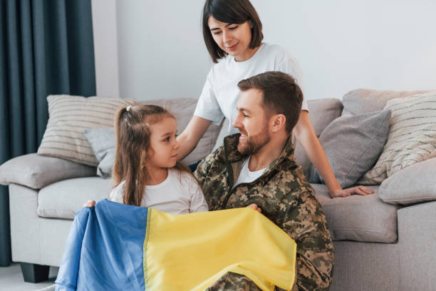 with ukrainian flag. soldier in uniform is at home with his wife and daughter - domestic life young family family child imagens e fotografias de stock