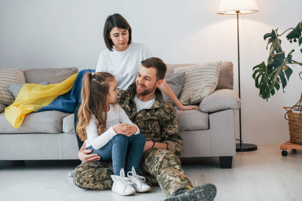 with ukrainian flag. soldier in uniform is at home with his wife and daughter - domestic life young family family child imagens e fotografias de stock