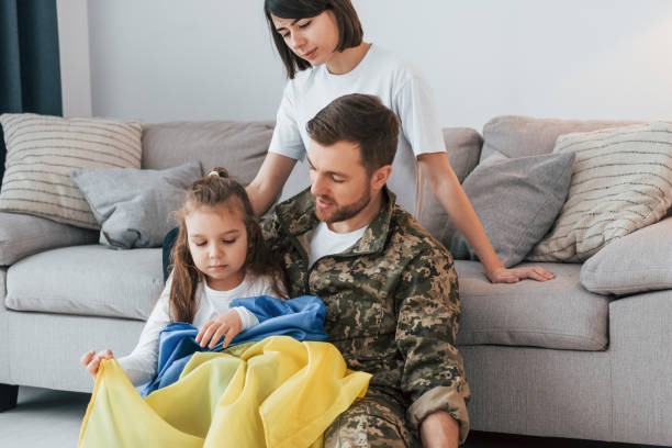 with ukrainian flag. soldier in uniform is at home with his wife and daughter - domestic life young family family child imagens e fotografias de stock