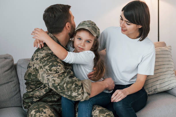 on the sofa. soldier in uniform is at home with his wife and daughter - domestic life young family family child imagens e fotografias de stock