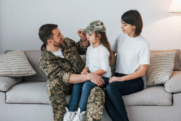 on the sofa. soldier in uniform is at home with his wife and daughter - domestic life young family family child imagens e fotografias de stock