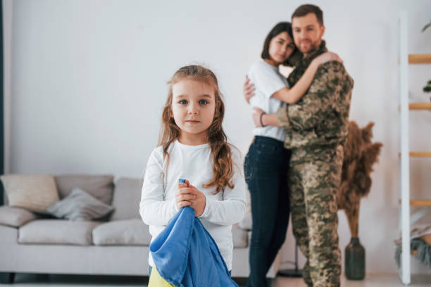 little girl holding ukraine flag. soldier in uniform is at home with his wife and daughter - domestic life young family family child imagens e fotografias de stock