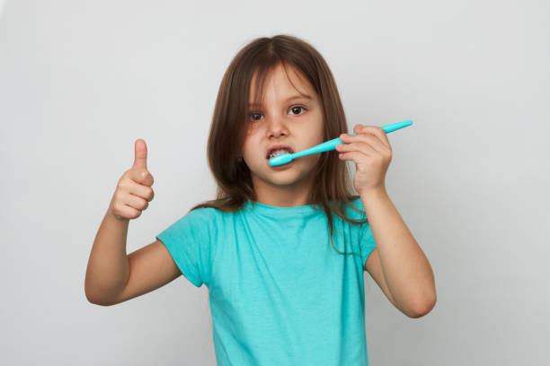 istock Child girl brushing teeth, white background with copy space 1392135059