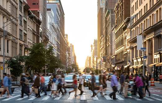 Diverse crowd of people walking across the busy intersection of 23rd Street  and 5th Avenue in Manhattan New York City NYC