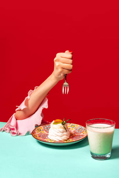 photographie pop art culinaire. portrait recadré d’une femme dégustant un gâteau sucré au pamplemousse sur fond rouge vif. intérieur vintage de style rétro - image created 1990s photos et images de collection