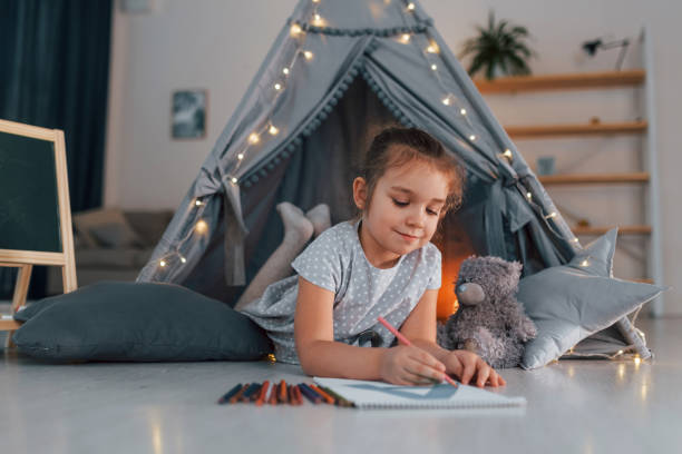 pisanie listu. urocza dziewczynka bawiąca się w namiocie, który znajduje się w pokoju domowym - domestic tent zdjęcia i obrazy z banku zdjęć