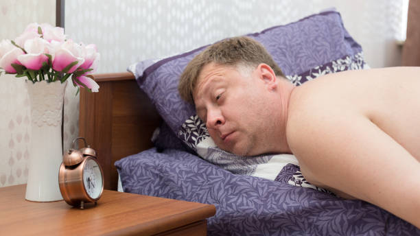um homem adulto de 40 a 45 anos está dormindo em sua cama sem ouvir um despertador alto - 40 45 years fotos - fotografias e filmes do acervo