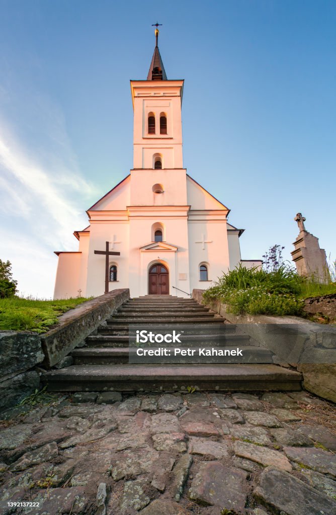 Small old christian church with a graveyard in front in the golden hour. Saint Ignatius Church in Malenovice, Czech Republic. Small old christian church with a graveyard in front in the golden hour. Saint Ignatius Church in Malenovice, Czechia 17th Century Stock Photo