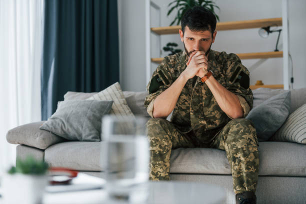 istock On the sofa. Post traumatic stress disorder. Soldier in uniform sitting indoors 1392138089