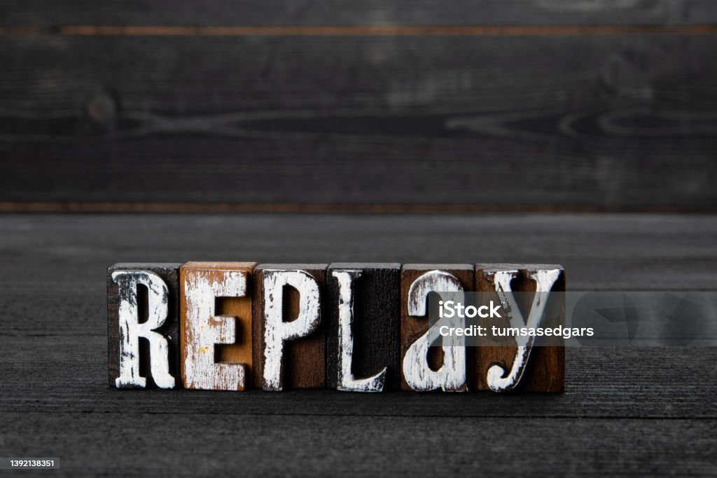 Replay. Text on a dark textured wooden background Replay. Text on a dark textured wooden background. Replay Stock Photo