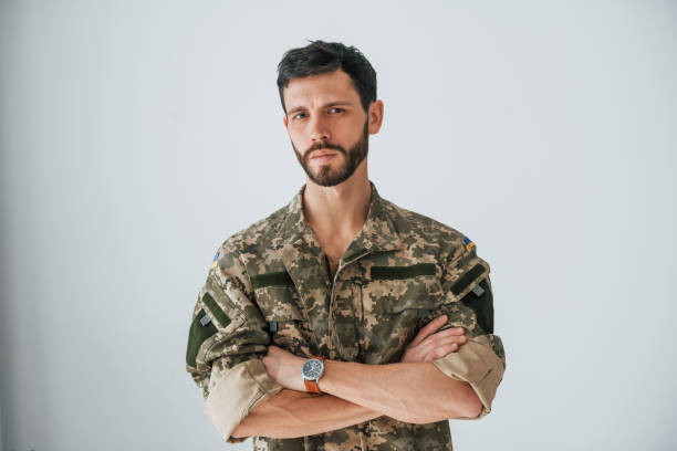 istock Soldier in uniform is standing indoors against white wall 1392138688