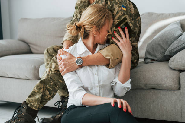 Soldier with his wife sitting indoors and embracing stock photo