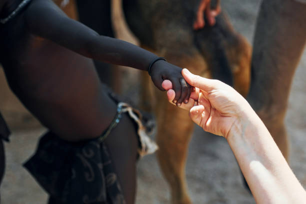 Touching hands, greetings gesture. Tourists is in Namibia with African kids.
