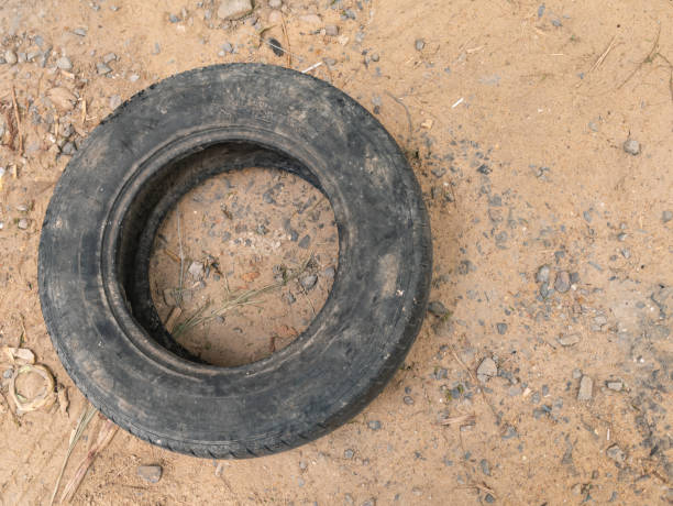 un vieux pneu de voiture noir gît sur le sol sablonneux. - tire track egypt track africa photos et images de collection