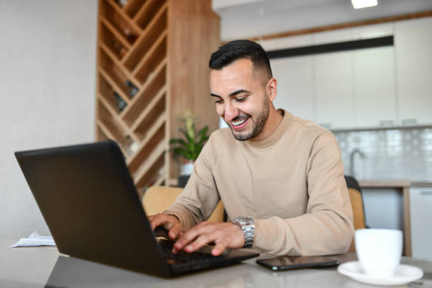 istock Smiling Male Enjoying Working From Home On Laptop And Drinking Coffee 1392140877
