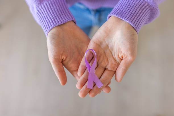 mujer irreconocible sosteniendo en sus manos una cinta púrpura - purple ribbon fotografías e imágenes de stock