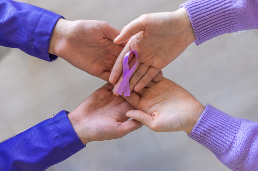 Unrecognizable man and woman holding in their hands purple ribbon