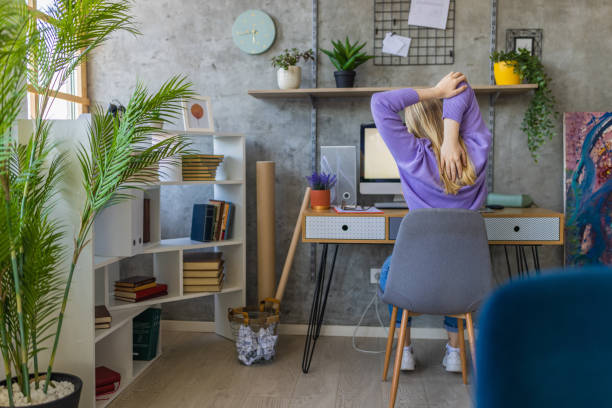 istock Caucasian young woman stretching while working from home office 1392143300