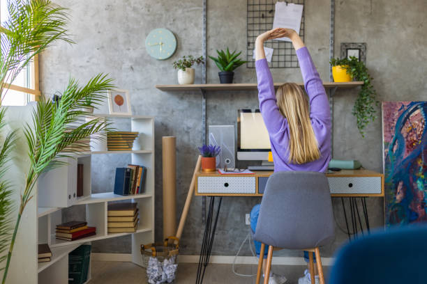 istock Caucasian young woman stretching while working from home office 1392143367